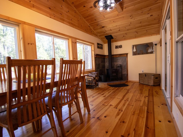 dining area with a wood stove, vaulted ceiling, light wood-type flooring, and wooden ceiling