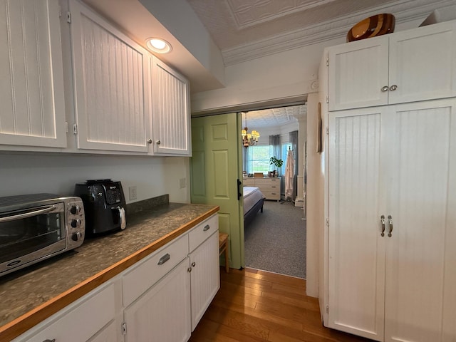 412 N Lubec Rd, Lubec, ME 04652 - kitchen featuring dark countertops, white cabinets, ornamental molding, wood finished floors, and a chandelier