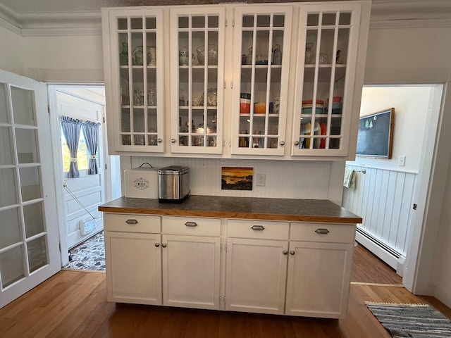 412 N Lubec Rd, Lubec, ME 04652 - kitchen with dark countertops, glass insert cabinets, ornamental molding, wood finished floors, and a baseboard heating unit