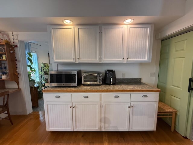 412 N Lubec Rd, Lubec, ME 04652 - kitchen featuring stainless steel microwave, white cabinets, and wood finished floors