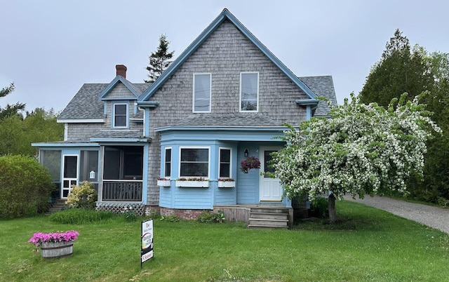 412 N Lubec Rd, Lubec, ME 04652 - view of front of house featuring a chimney, a front yard, roof with shingles, and a sunroom