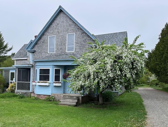 412 N Lubec Rd, Lubec, ME 04652 - view of front of house featuring roof with shingles, a front lawn, and a sunroom