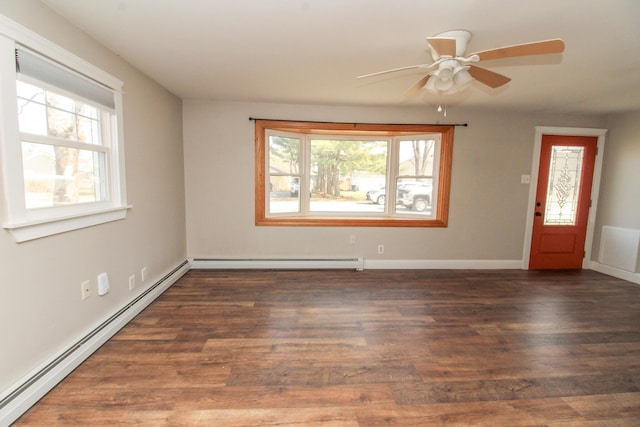 empty room featuring a healthy amount of sunlight, a baseboard heating unit, and wood finished floors