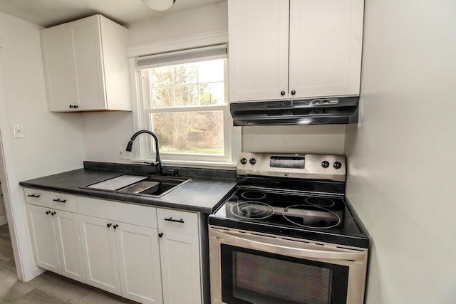 kitchen featuring stainless steel electric range oven, dark countertops, a sink, under cabinet range hood, and white cabinetry