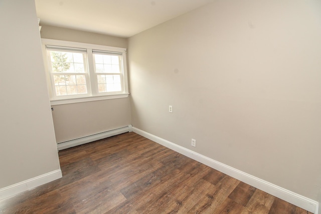 spare room with baseboards, a baseboard heating unit, and dark wood-style flooring
