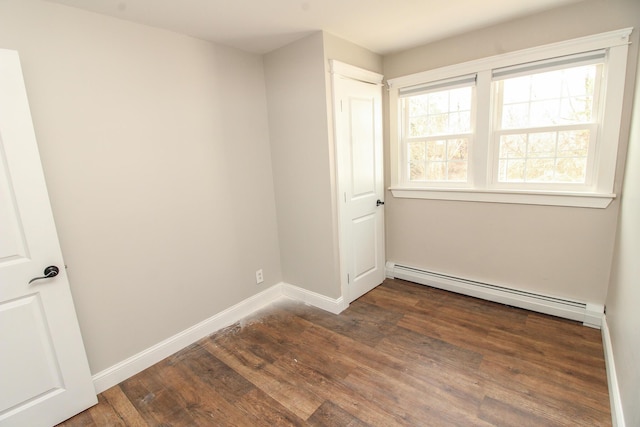 unfurnished room featuring baseboards, wood finished floors, and a baseboard radiator