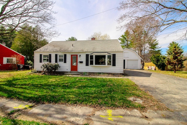 view of front of house featuring aphalt driveway, a chimney, an outbuilding, a detached garage, and a front lawn