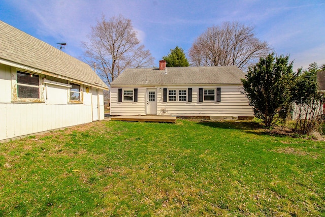 back of property featuring a chimney, a yard, and a deck