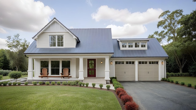 modern farmhouse featuring covered porch, metal roof, a front lawn, and aphalt driveway