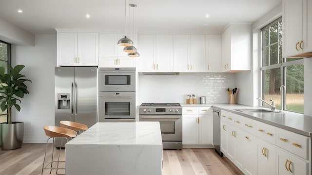 kitchen with white cabinetry, stainless steel appliances, backsplash, and light wood-type flooring