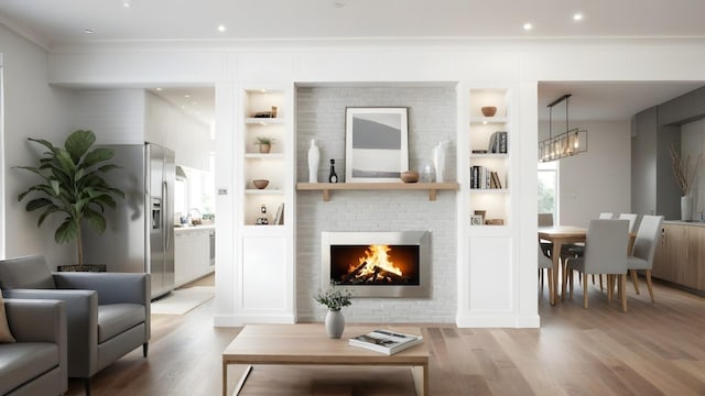 living area featuring crown molding, light wood-type flooring, plenty of natural light, and built in shelves