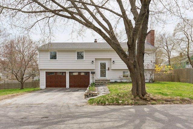 split foyer home featuring a chimney, fence, an attached garage, concrete driveway, and entry steps