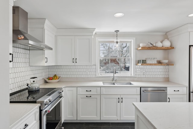 kitchen featuring a sink, backsplash, wall chimney range hood, white cabinets, and appliances with stainless steel finishes