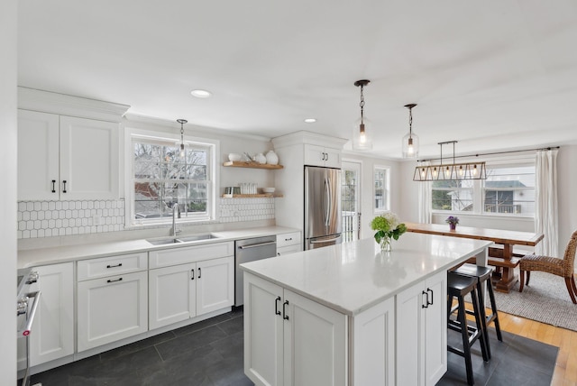 kitchen featuring a sink, a kitchen bar, backsplash, white cabinets, and appliances with stainless steel finishes