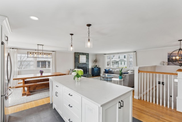kitchen featuring freestanding refrigerator, pendant lighting, a center island, a chandelier, and white cabinets