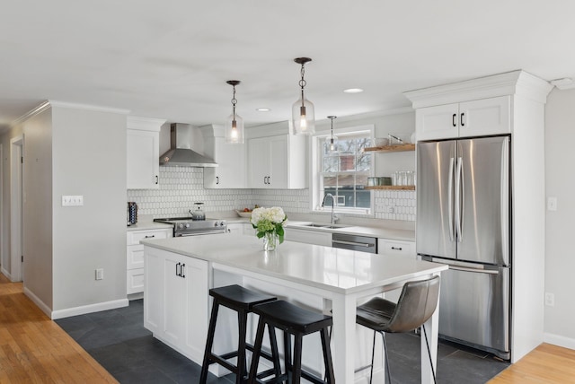 kitchen with a sink, wall chimney range hood, light countertops, white cabinets, and appliances with stainless steel finishes