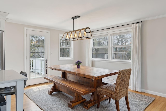 dining space with crown molding, a notable chandelier, light wood-type flooring, and baseboards