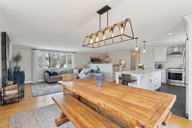 dining room with a notable chandelier, a baseboard radiator, baseboard heating, recessed lighting, and wood finished floors