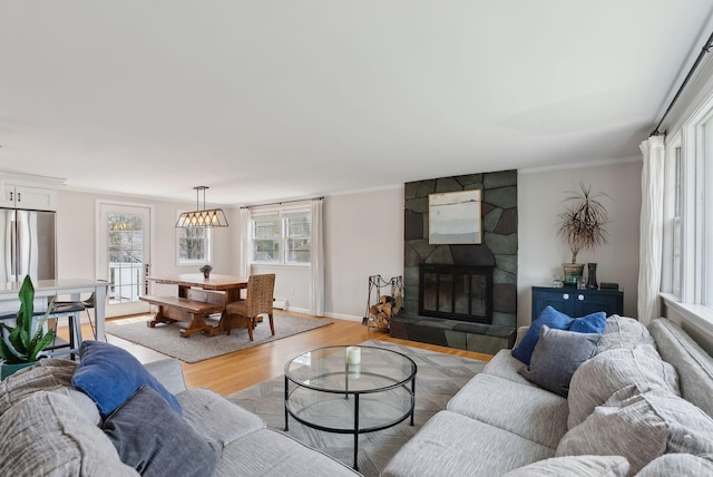 living area featuring baseboards, light wood-style floors, a fireplace, and crown molding