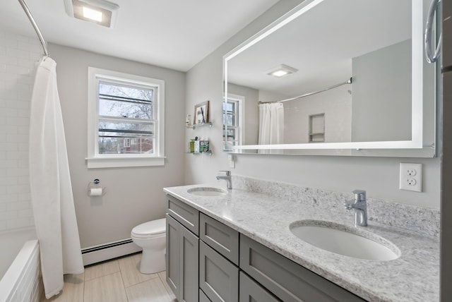 full bathroom featuring double vanity, toilet, a baseboard heating unit, and a sink