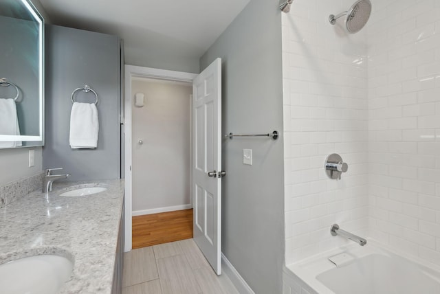 bathroom with double vanity, tub / shower combination, baseboards, and a sink