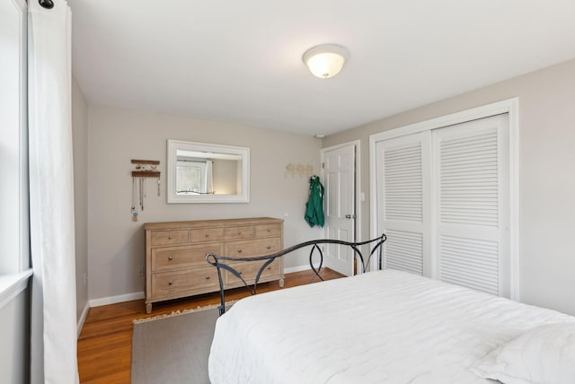 bedroom with a closet, baseboards, and wood finished floors