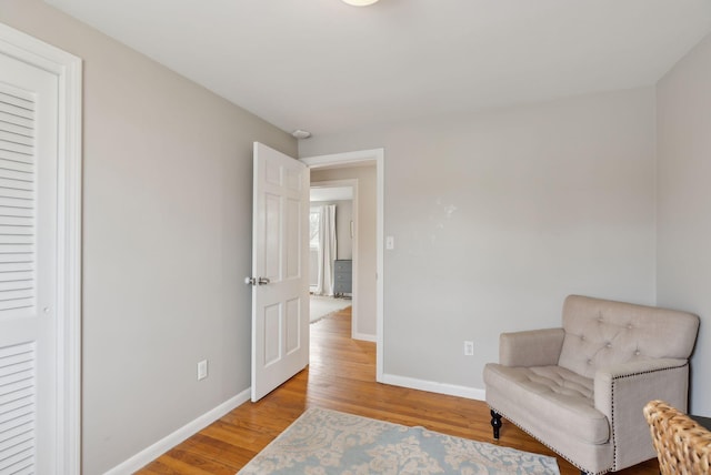 sitting room with baseboards and light wood-style flooring