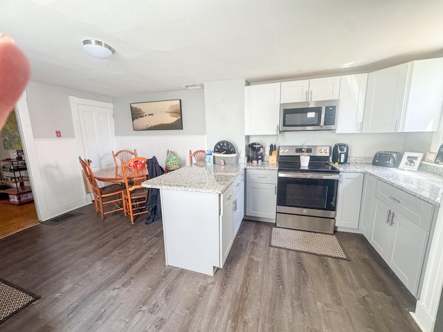 6 Hudson St, Bangor, ME 04401 - kitchen with dark wood-style flooring, stainless steel appliances, a peninsula, and a wainscoted wall