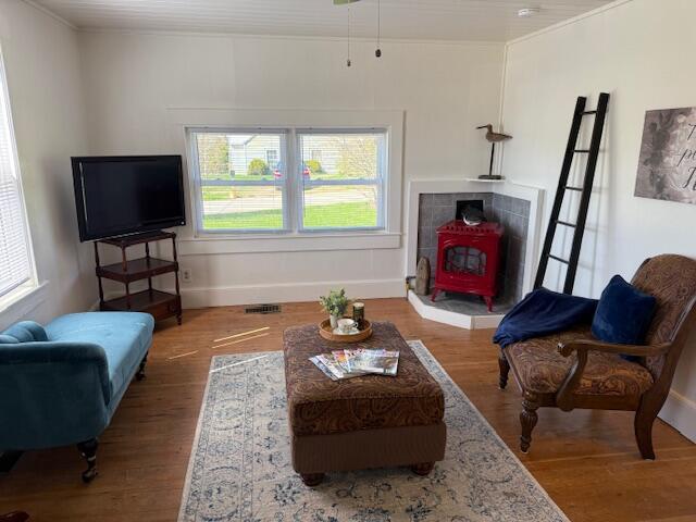 7 Johnson St, Eastport, ME 04631 - living area featuring a wealth of natural light, a wood stove, crown molding, and wood finished floors