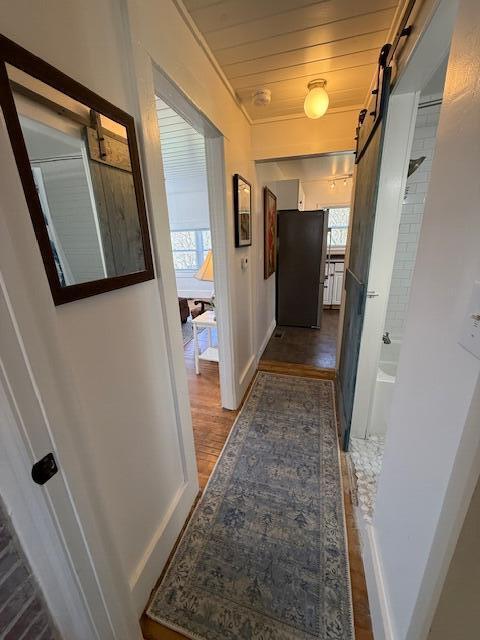 7 Johnson St, Eastport, ME 04631 - hall featuring a barn door, baseboards, a healthy amount of sunlight, and wood finished floors
