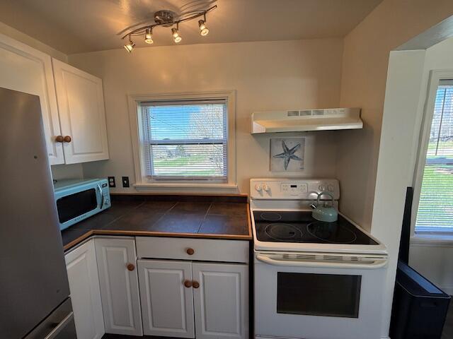 7 Johnson St, Eastport, ME 04631 - kitchen with under cabinet range hood, white appliances, and white cabinets
