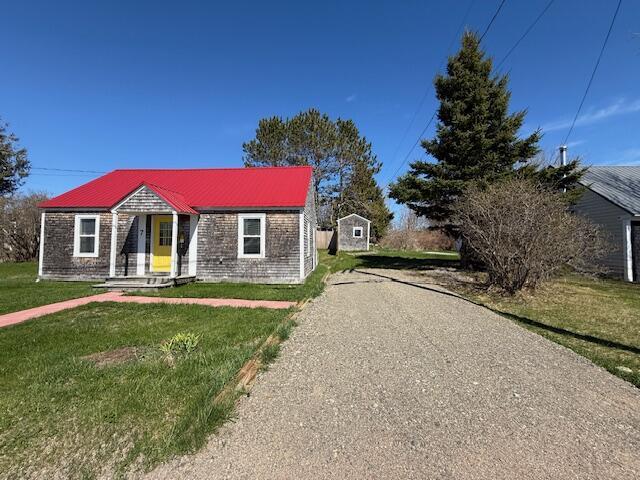7 Johnson St, Eastport, ME 04631 - bungalow-style house featuring metal roof, a storage shed, an outdoor structure, and a front yard