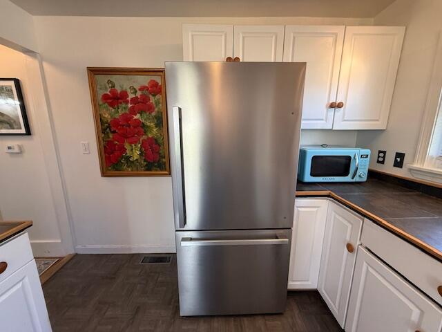 7 Johnson St, Eastport, ME 04631 - kitchen with freestanding refrigerator, baseboards, visible vents, dark countertops, and white cabinets