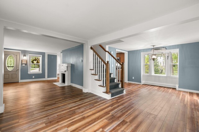 8 Organug Rd, York, ME 03909 - unfurnished living room featuring a baseboard radiator, stairway, wood-type flooring, a brick fireplace, and baseboards