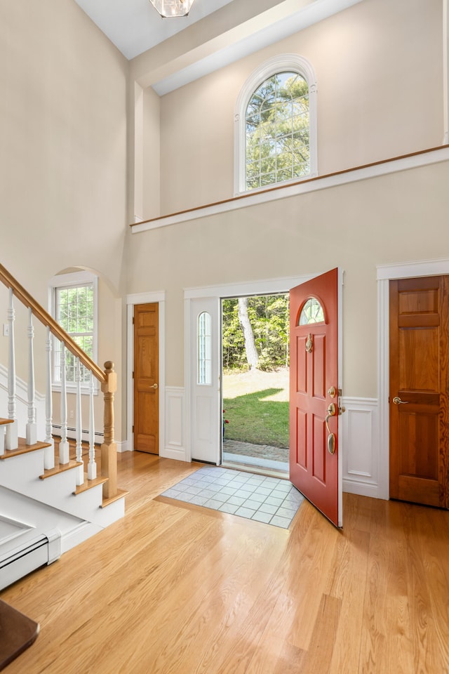 148 Hunter Way, Falmouth, ME 04105 - entryway with a towering ceiling, wood finished floors, a baseboard heating unit, a decorative wall, and a wainscoted wall