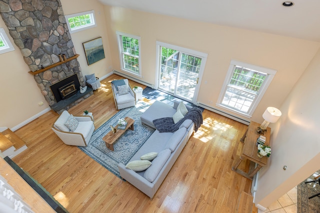 148 Hunter Way, Falmouth, ME 04105 - living room with wood finished floors, a fireplace, a baseboard radiator, baseboards, and a high ceiling