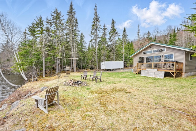 view of grassy yard featuring a fire pit and a wooden deck