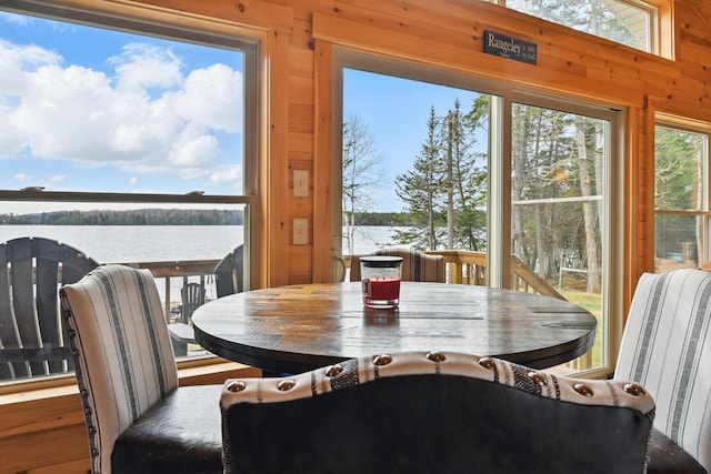 dining space with a water view and wood walls