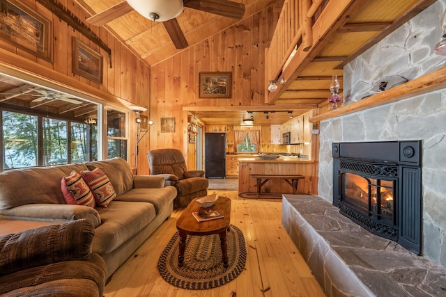 129 Diller Line Rd, Chesterville, ME 04938 - living room with a ceiling fan, wooden ceiling with exposed beams, light wood finished floors, a fireplace, and wood walls
