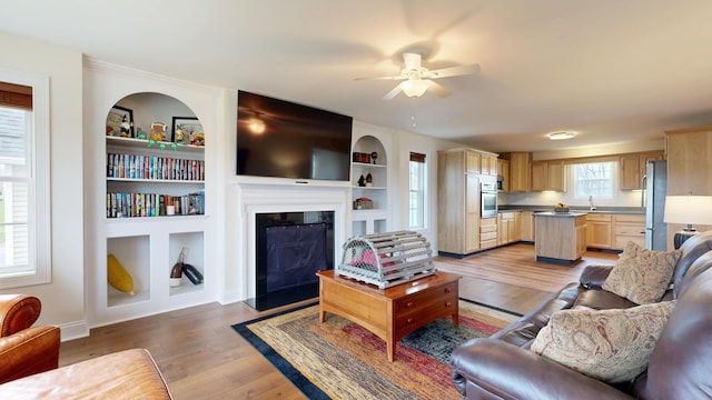 48 Lubear Way, Auburn, ME 04210 - living area with a ceiling fan, light wood finished floors, a fireplace with flush hearth, built in shelves, and baseboards