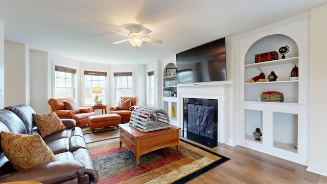 48 Lubear Way, Auburn, ME 04210 - living area featuring ceiling fan, wood finished floors, built in shelves, a glass covered fireplace, and baseboards