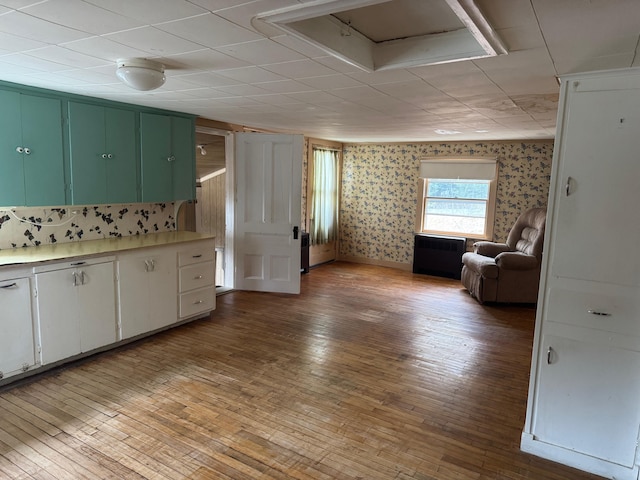 6 Mcdevitt Ln, Eastbrook, ME 04634 - kitchen with light wood-type flooring, a paneled ceiling, light countertops, white cabinetry, and open floor plan