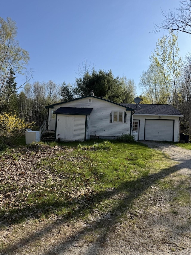 6 Mcdevitt Ln, Eastbrook, ME 04634 - view of front facade with a garage, dirt driveway, and a front lawn