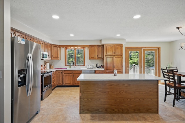 128 Capen Rd, Gardiner, ME 04345 - kitchen featuring brown cabinets, a healthy amount of sunlight, light countertops, and appliances with stainless steel finishes