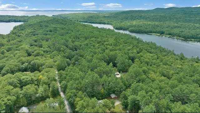 aerial view of property and surrounding area with a forest and a nearby body of water