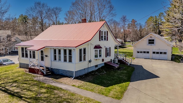 view of front of house with a chimney, metal roof, a front yard, an outbuilding, and a detached garage