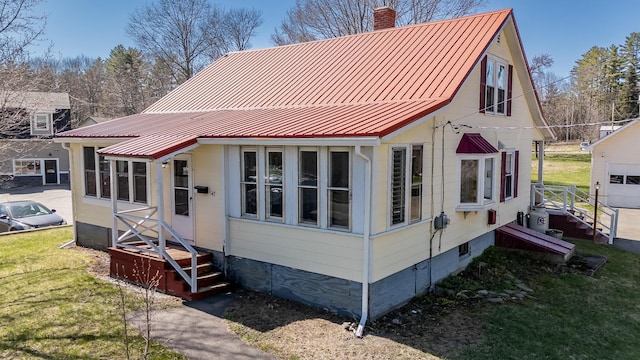 view of front of property featuring metal roof, a chimney, and a front yard