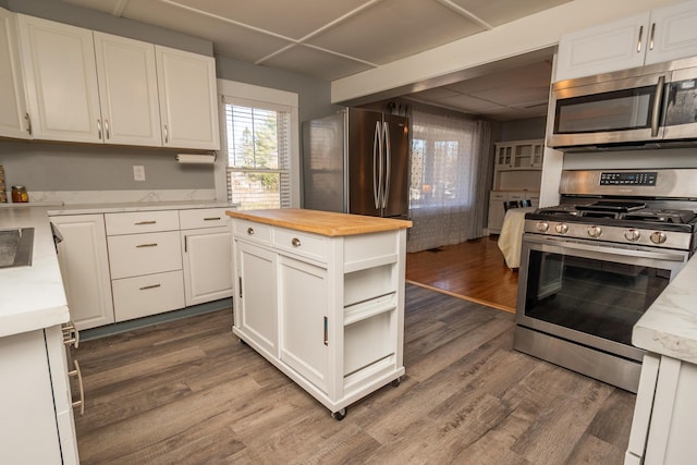 kitchen featuring wood counters, stainless steel appliances, dark wood-style floors, and white cabinets
