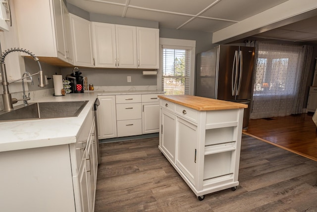kitchen featuring wooden counters, a sink, freestanding refrigerator, open shelves, and white cabinetry