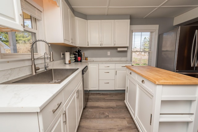 kitchen with a sink, dark wood finished floors, white cabinets, wooden counters, and appliances with stainless steel finishes